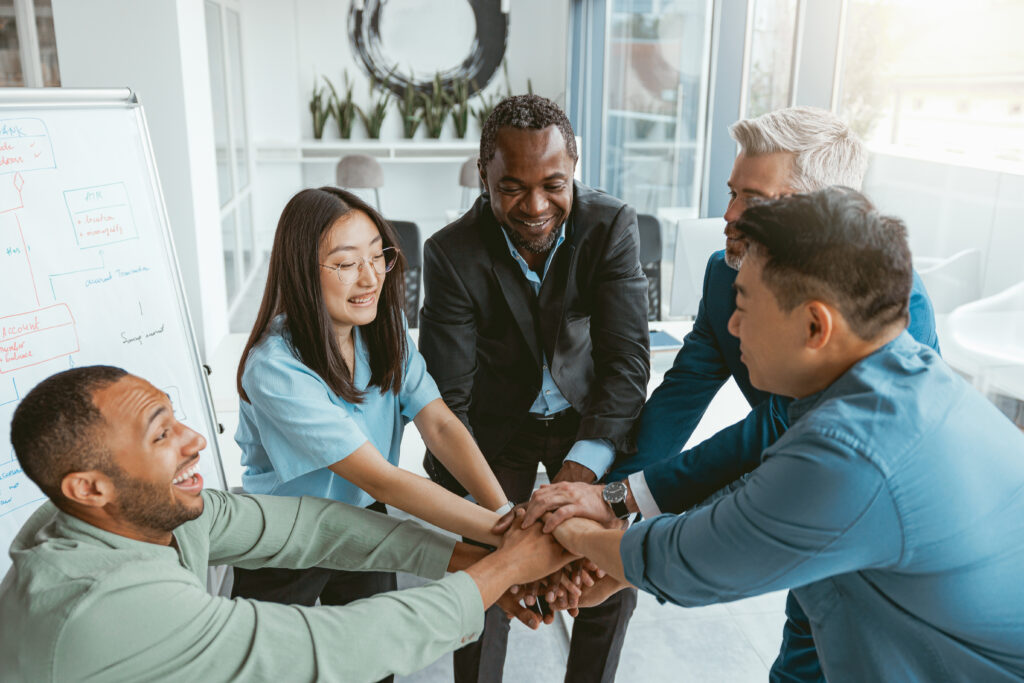 A team gathered with their hands together, showing a supportive work culture